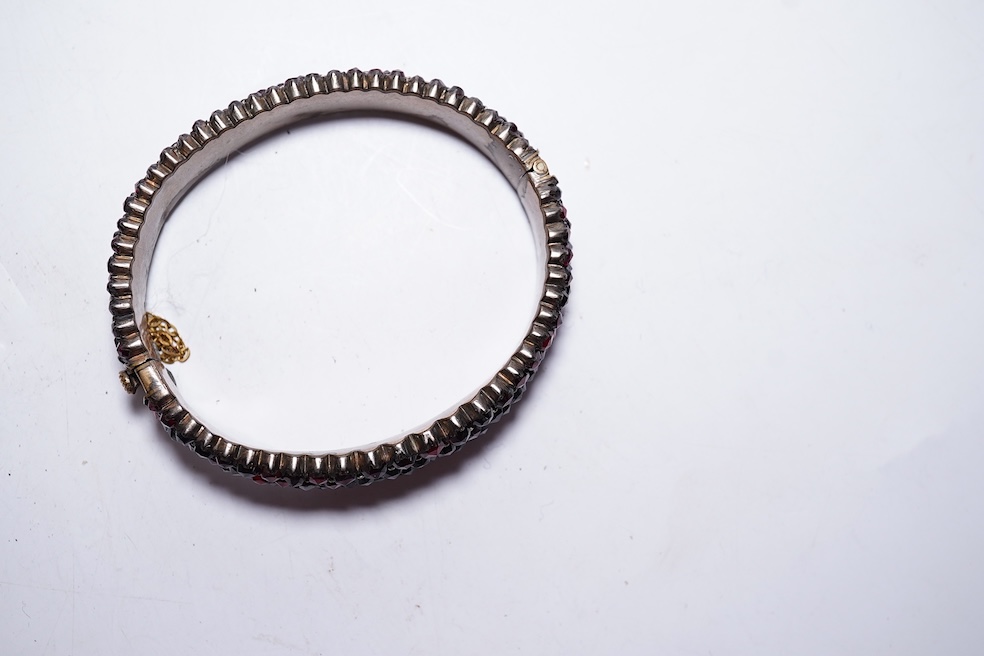 A suite of garnet and paste jewellery, comprising: a brooch, 5cm diameter; a bangle, inner circumference 16cm; two rings, sizes I and M; a pair of earrings, and a single earring, each set with rose-cut garnets; and a pai